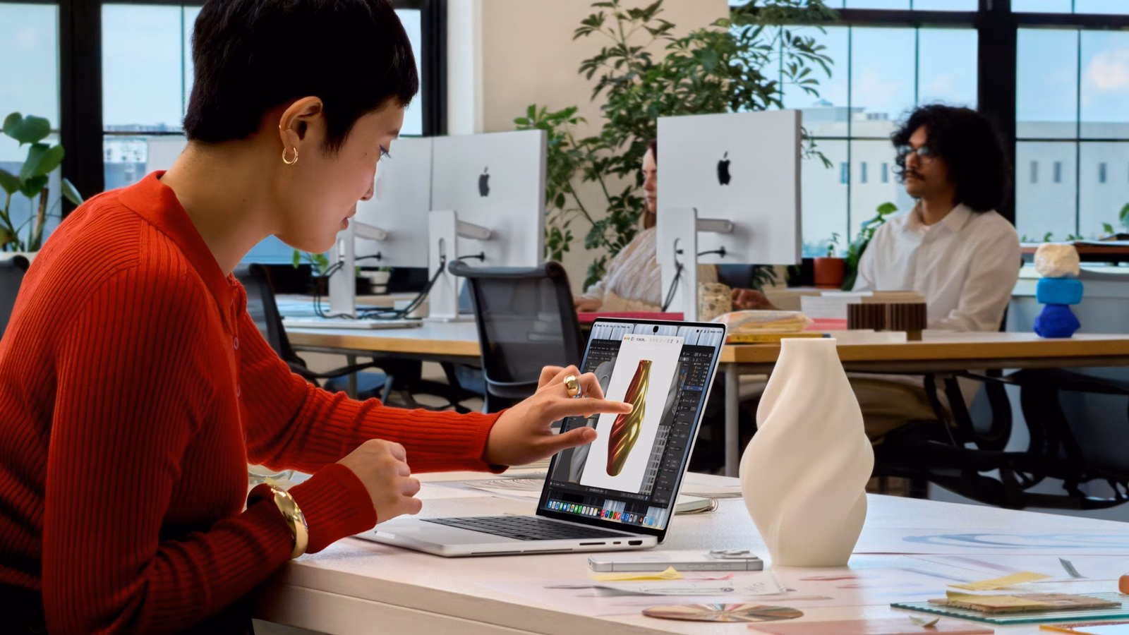 ผู้ใช้แตะจอ MacBook Pro จอ PROLED XDR ขณะทำงานในออฟฟิศ